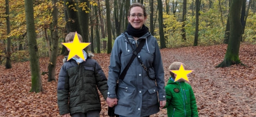 Gina steht mit ihren Kindern auf einem Waldweg und schaut in die Kamera